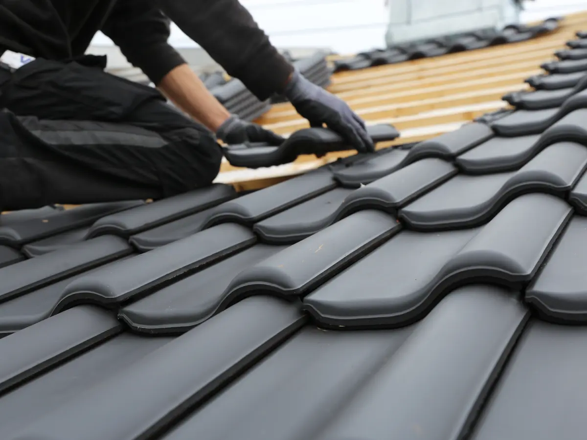 Roofer in gloves relaying tiles on new battens