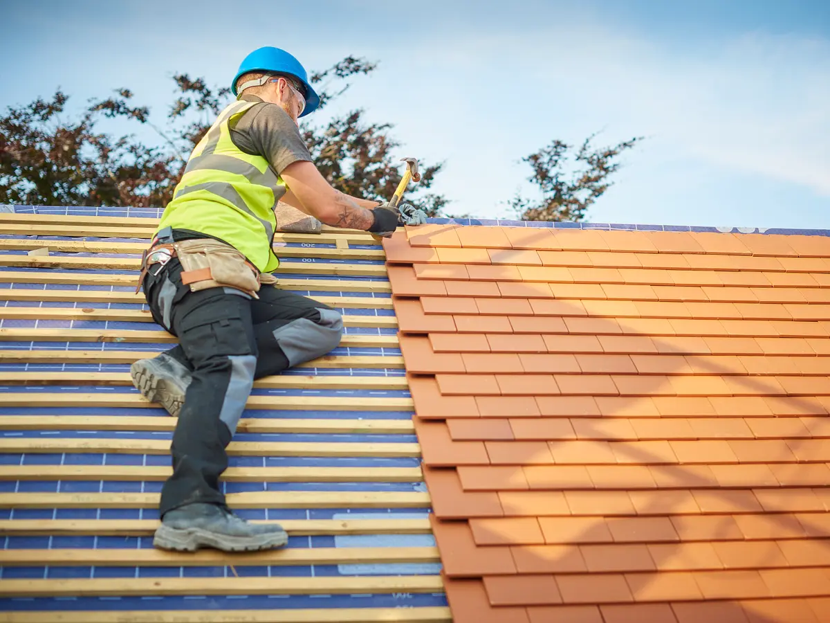Roofer fixing new roof covering in place on battens