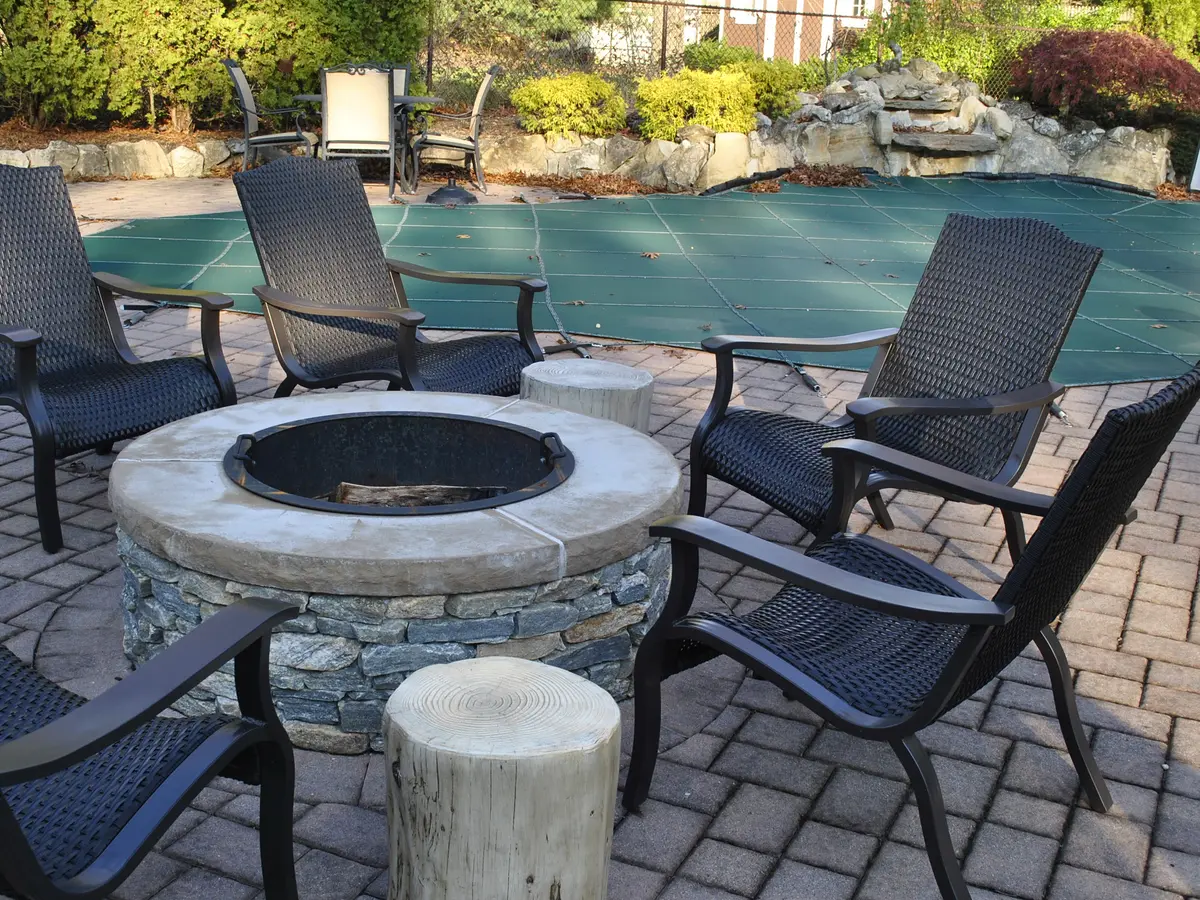 Paver patio with a stone fire pit and outdoor chairs