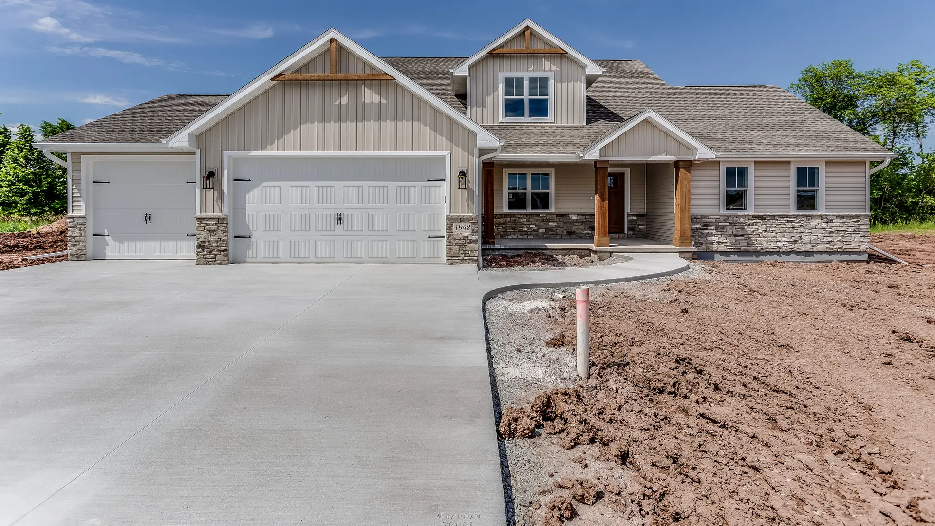 Detached house with a shingle roof, stone trim and a new concrete driveway