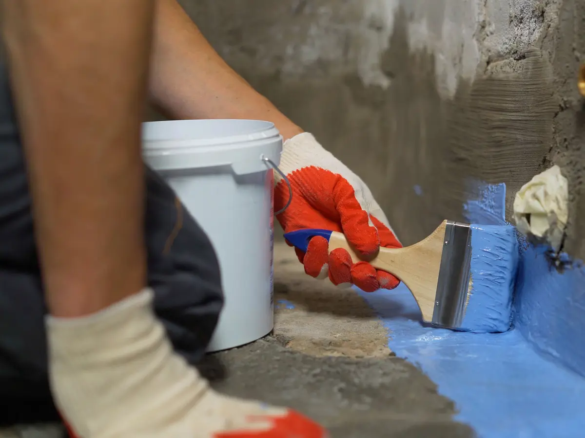 Sealant being brushed into the joint between a foundation wall and floor