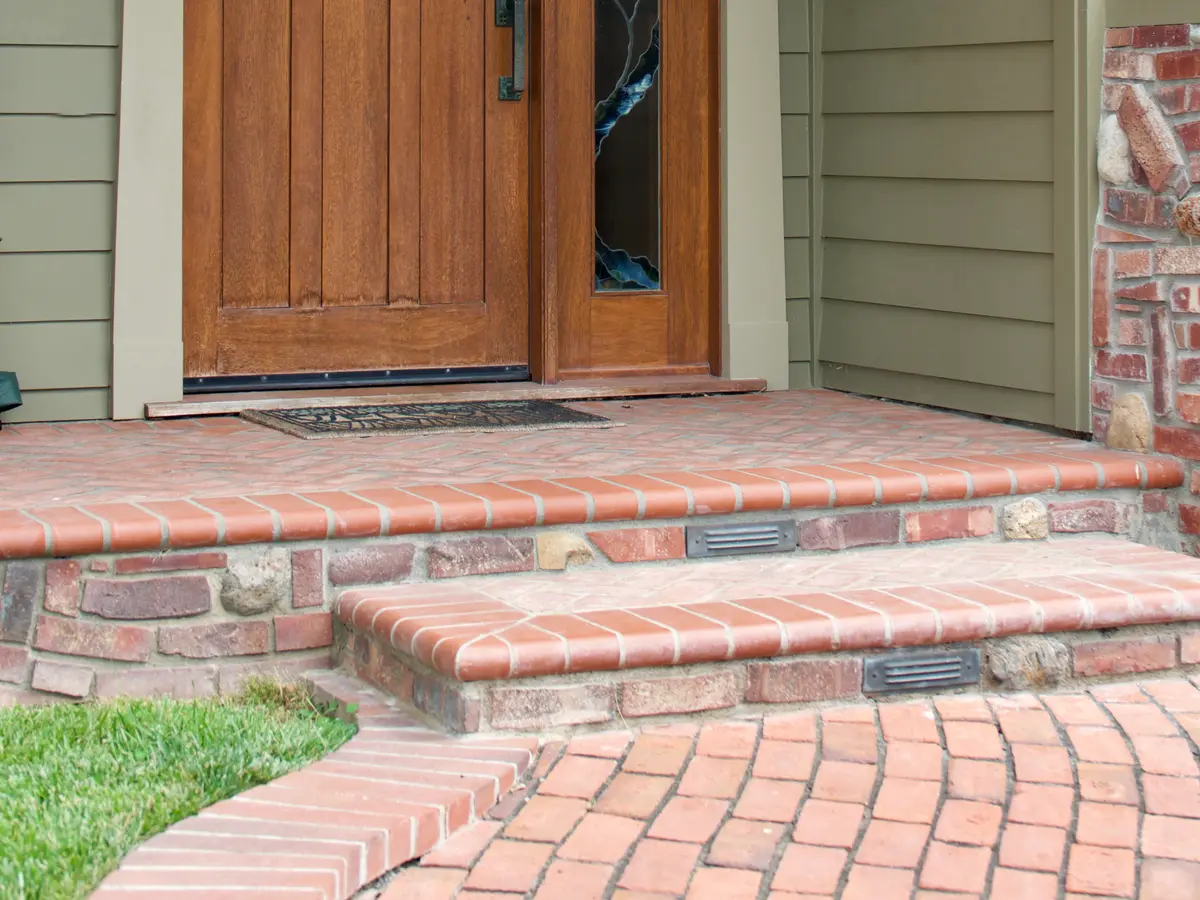 Brick and stone front steps up to a wooden door
