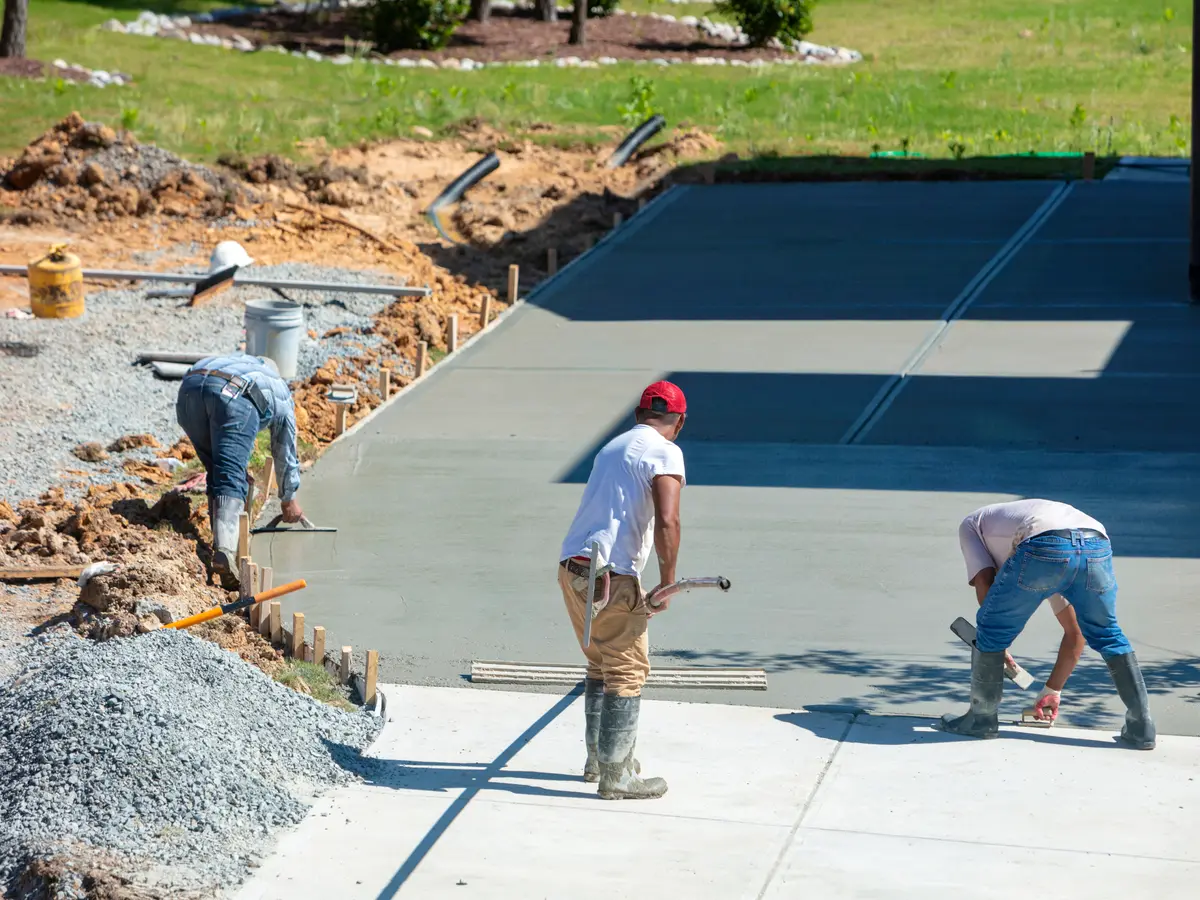 Workers finishing a new poured concrete driveway