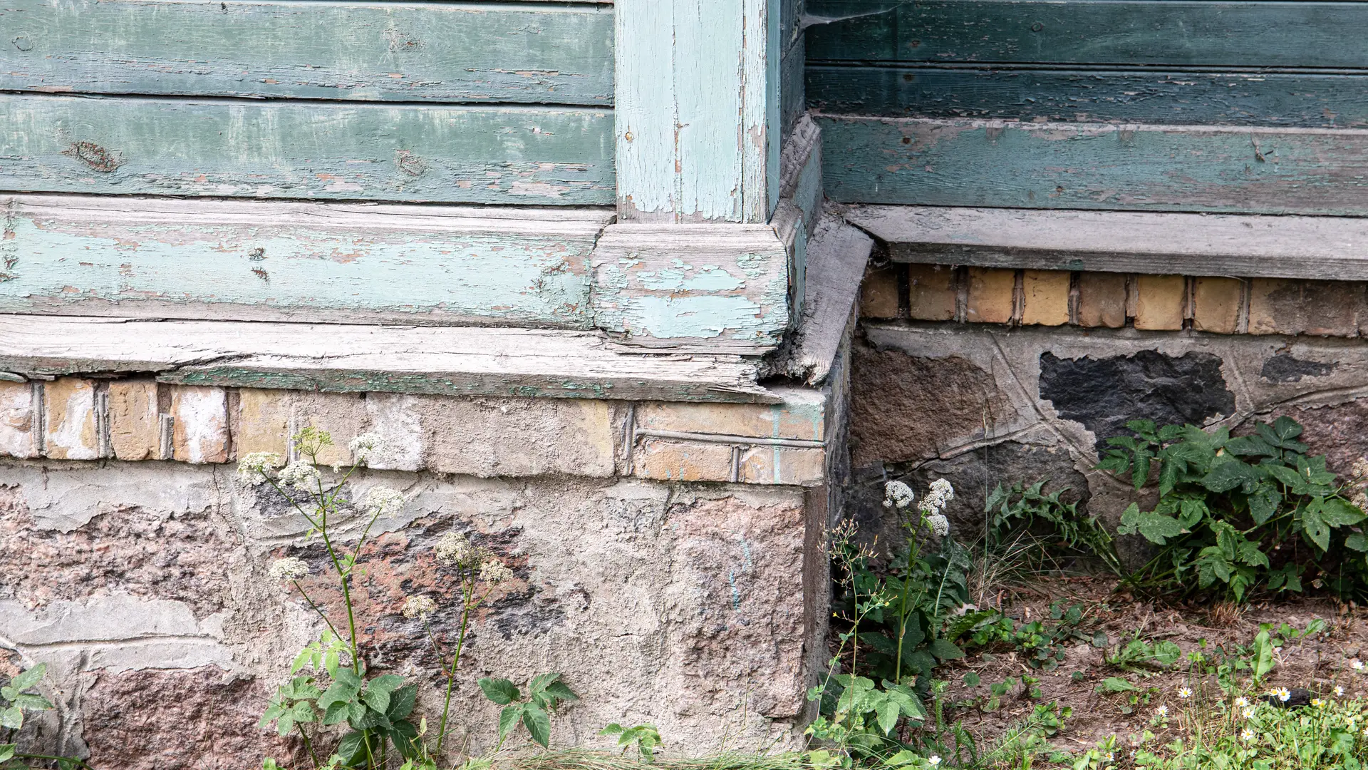 Old stone and brick foundation below the siding of a house