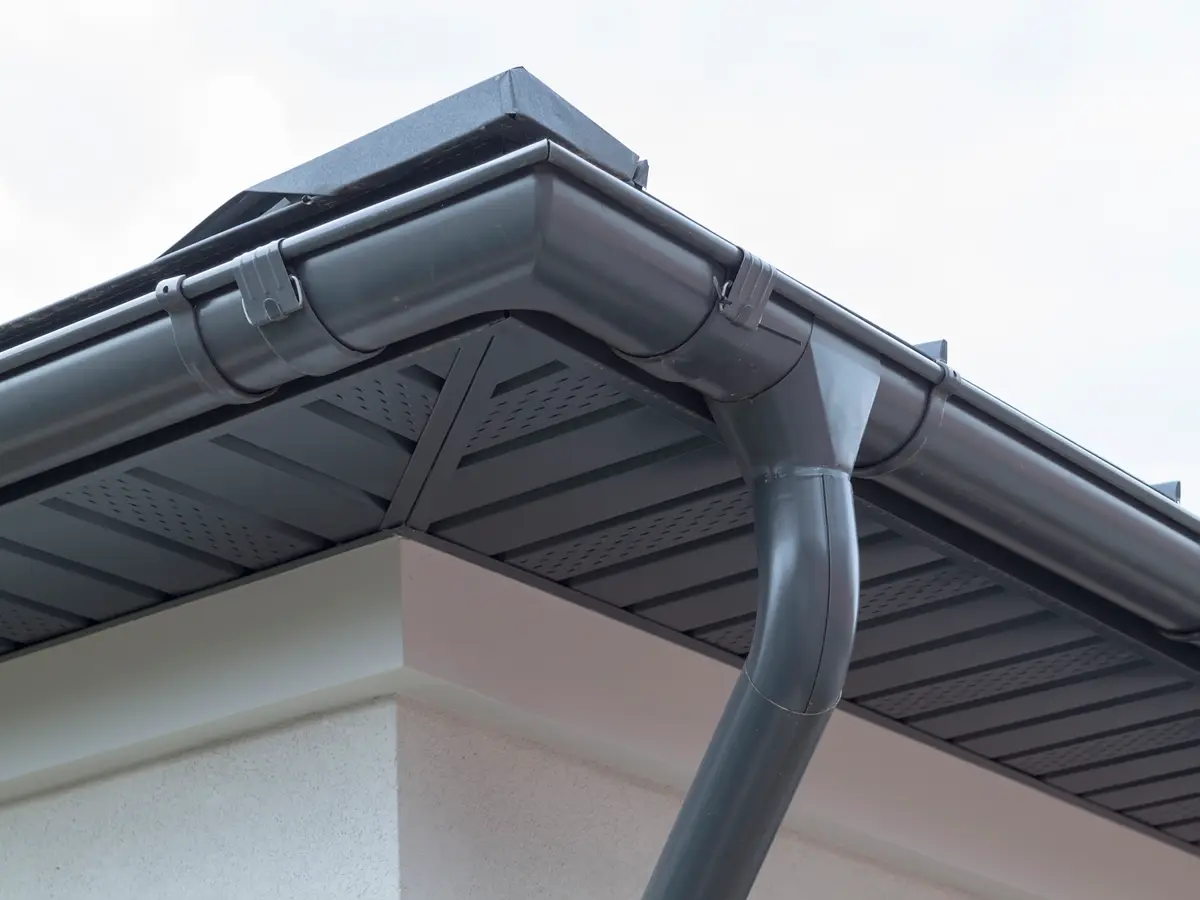 Grey eavestrough and downspout below a vented soffit
