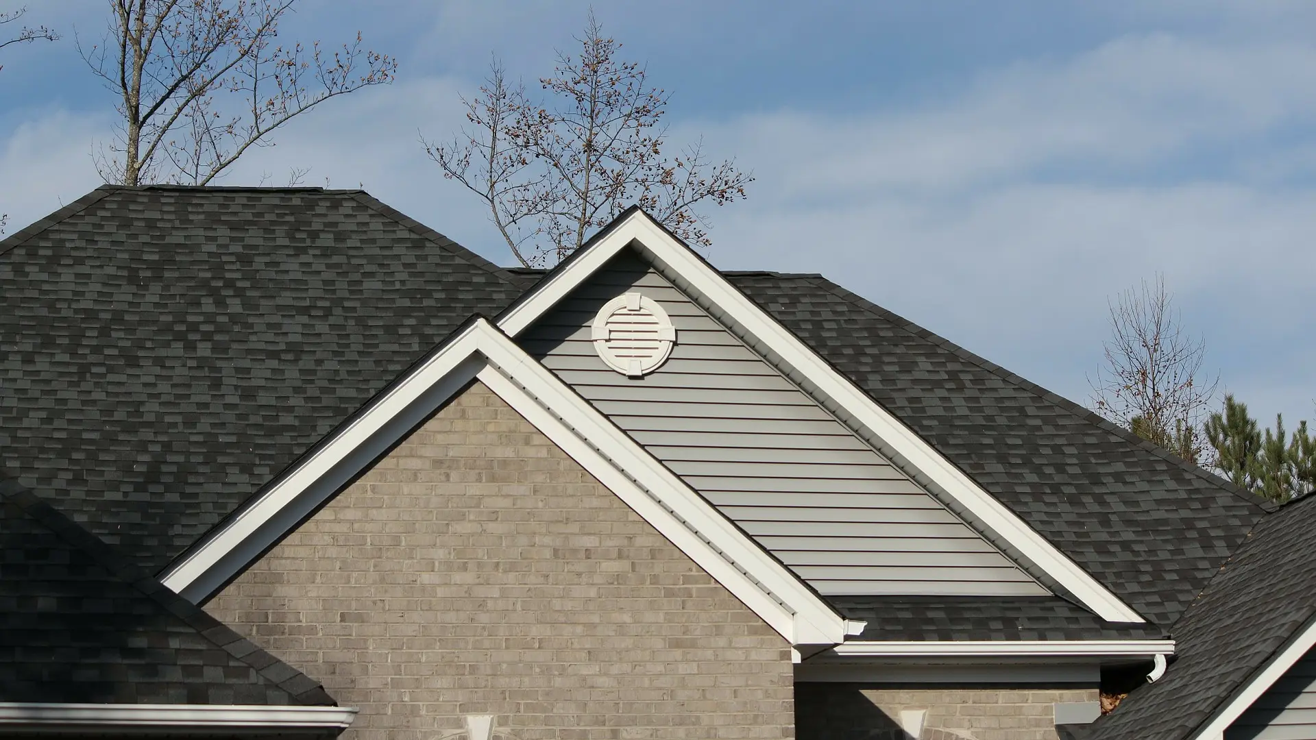 Shingle roofs, white fascia and siding gables on a brick house
