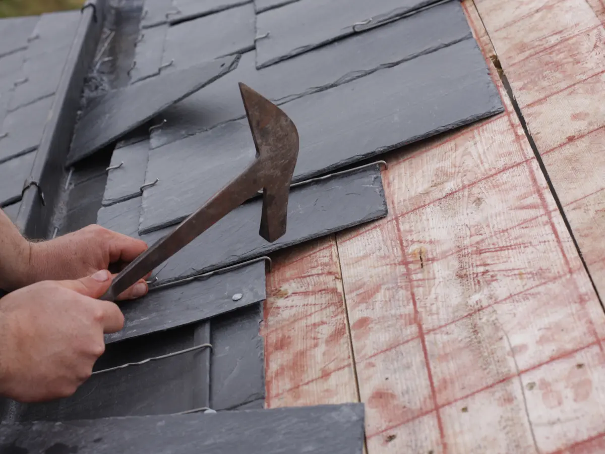 Roofer using a slate hammer to fit a new slate